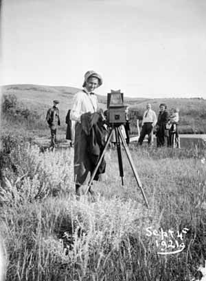 Evelyn Cameron standing next to her camera and tripod