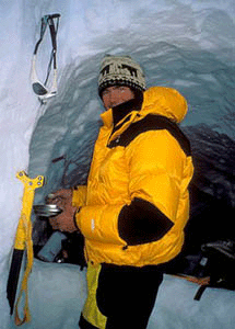 Alex Lowe in winter gear standing in front of an ice cave.